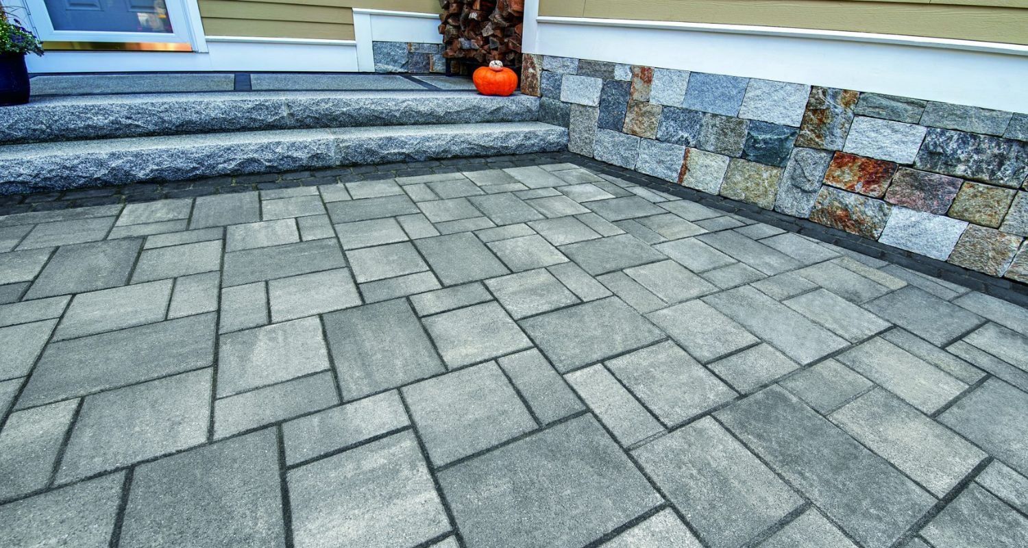A brick patio with steps and a pumpkin in front of a house.