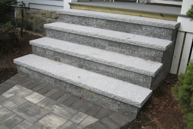 A set of granite steps leading up to a porch.