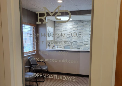 Glass door to RMD Dentistry office with frosted logo, hours, and waiting room visible inside
