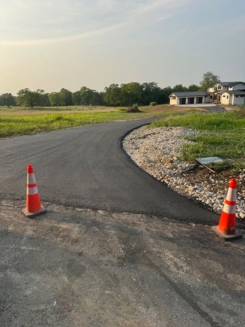 Two orange and white traffic cones on the side of a road