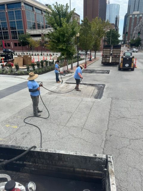 Two men are working on a sidewalk in a city