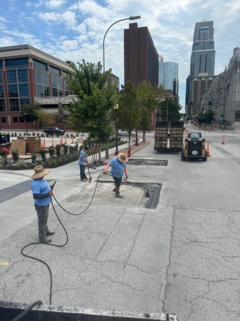 Two men are working on a sidewalk in a city