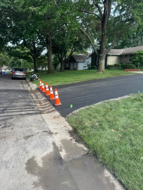 A row of orange and white traffic cones on the side of a road.