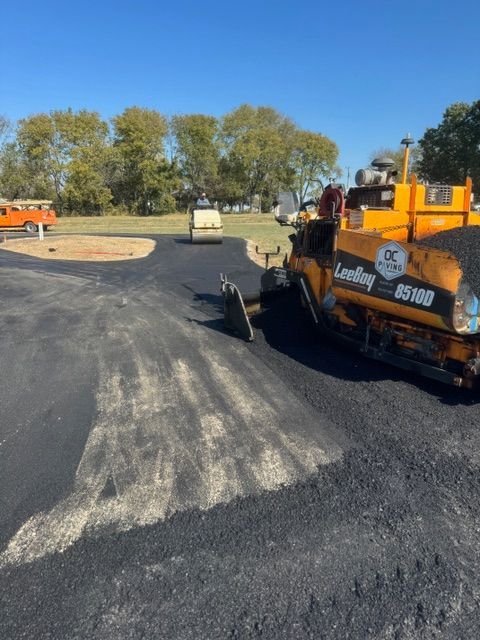 A bulldozer is laying asphalt on a road