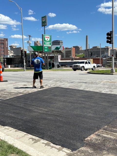 A man in a blue shirt is standing in the middle of a street