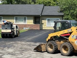 A yellow cat skid steer is parked in front of a house.
