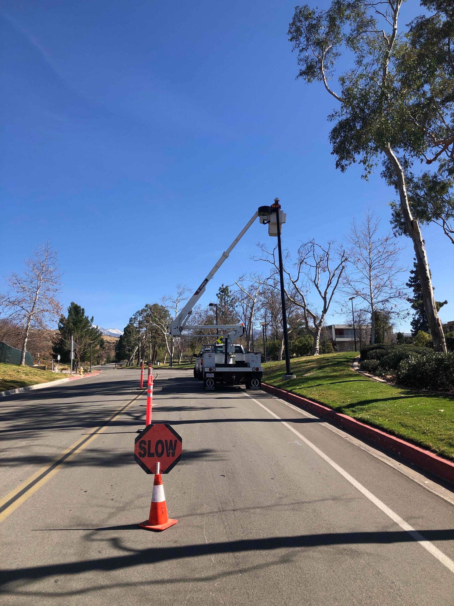 Roadwork on a sunny street with a STOP sign cone and a truck blocking the lane