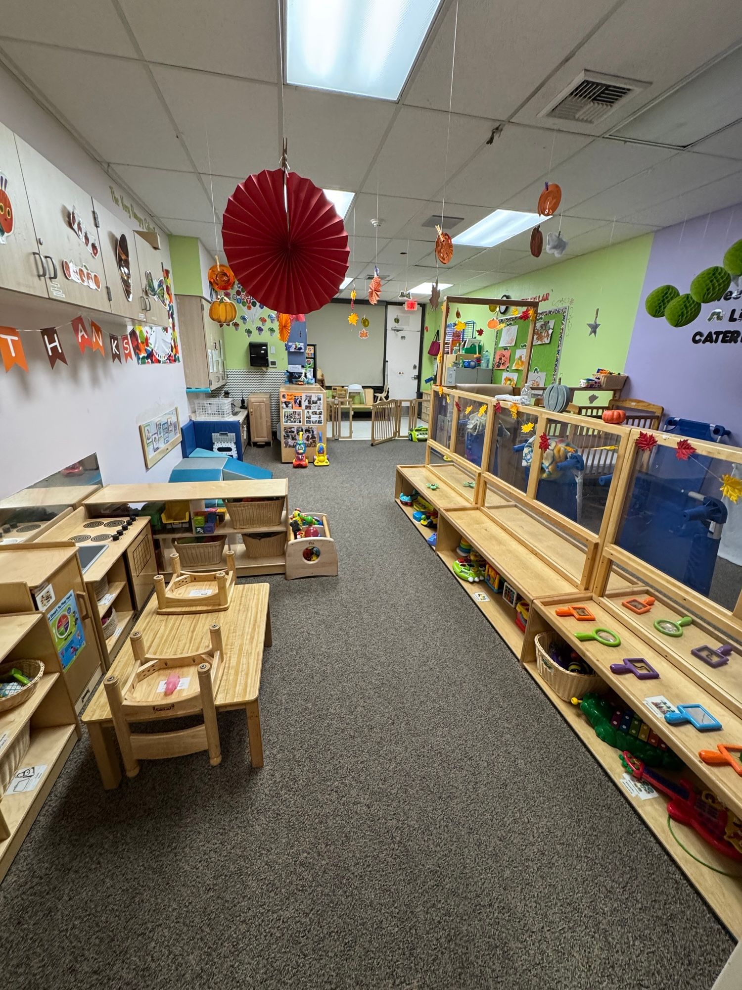 Colorful classroom with wooden play stations, toys, and a red hanging paper lantern