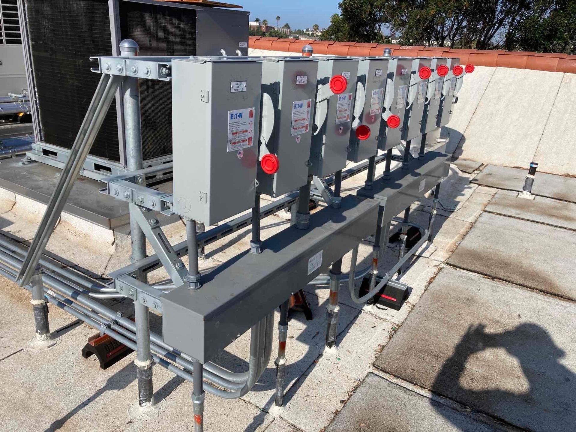 Industrial rooftop HVAC units with gray metal piping and red valve handles on a concrete roof