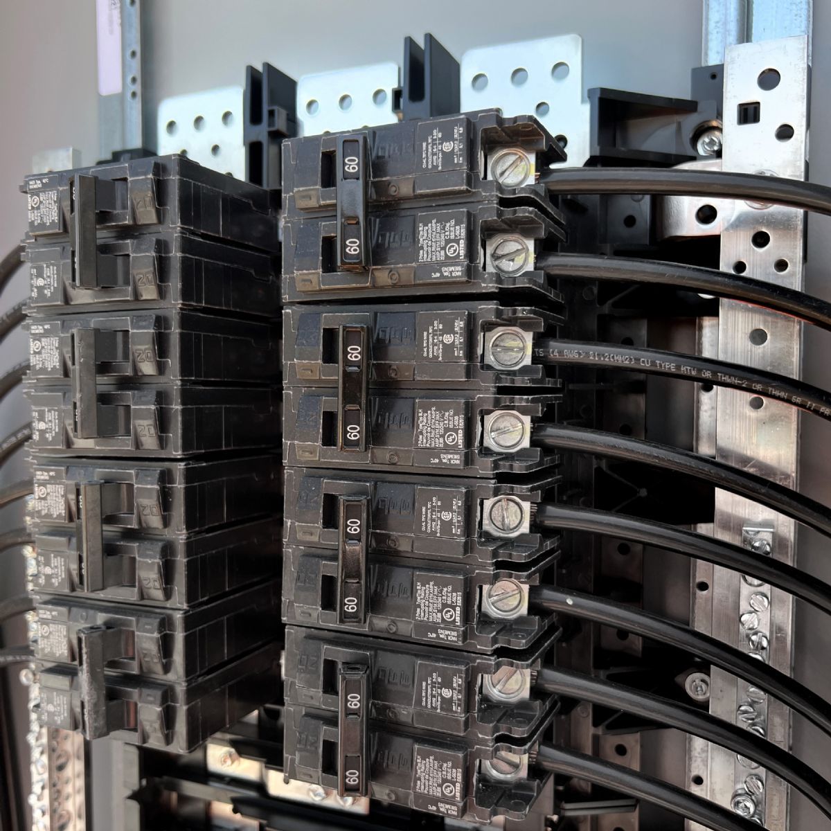 Electrical circuit breaker panel with multiple black breakers and connected wires
