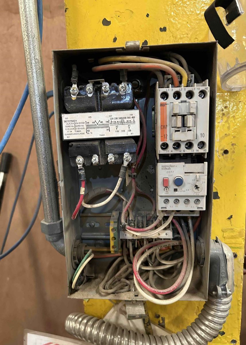 Open electrical control panel with wiring, relays, and conduit inside a yellow metal enclosure
