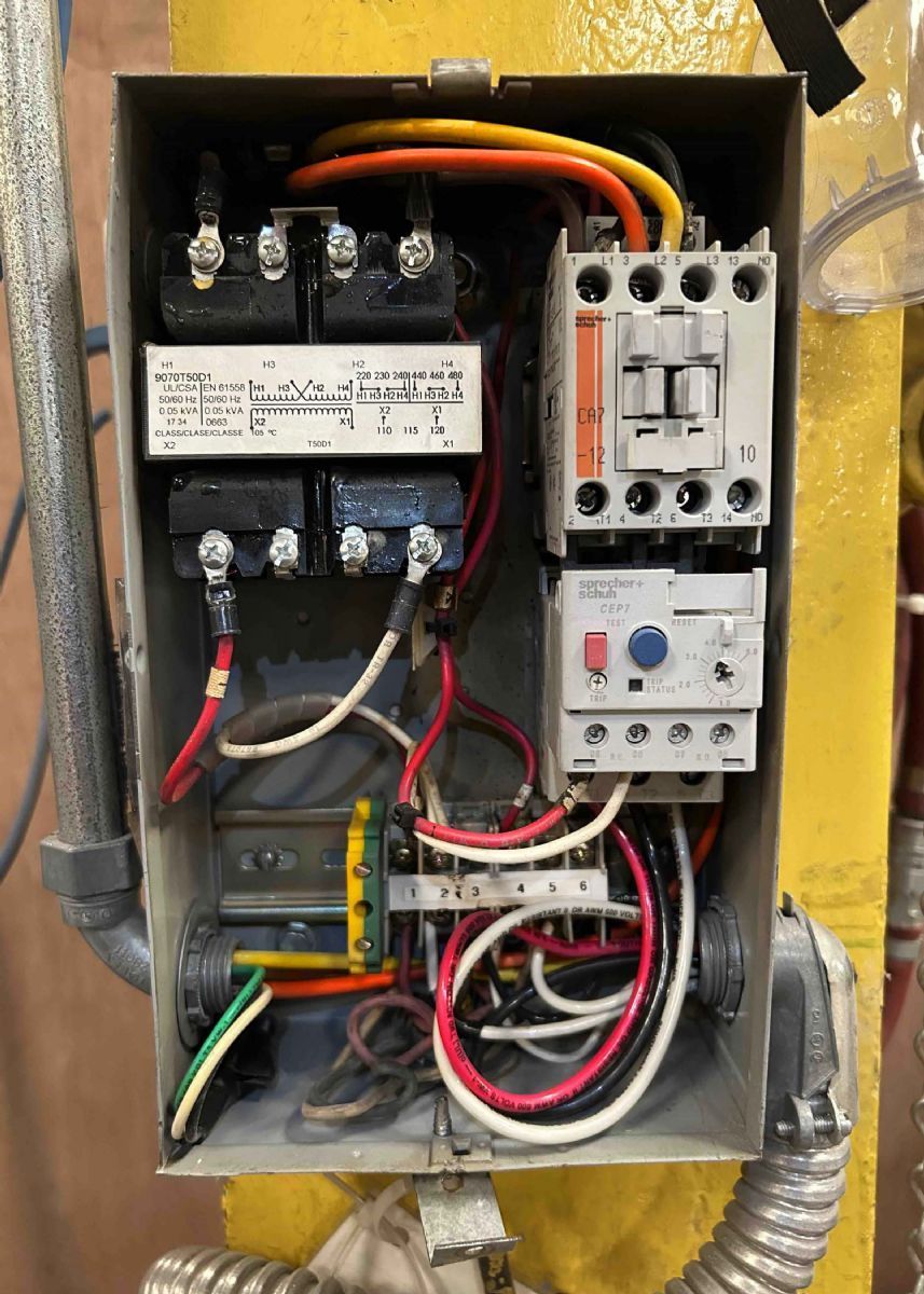 Open electrical control panel with wiring, relays, and switches inside a metal box