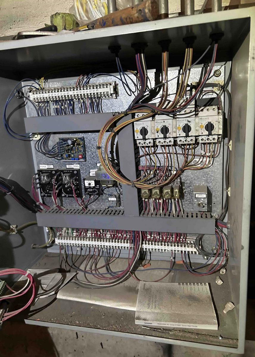 Open electrical control panel with wiring, relays, terminal blocks, and circuit modules inside a metal cabinet