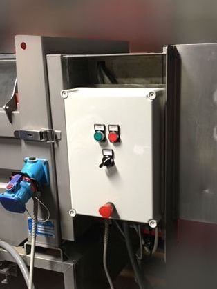 Industrial control panel with green and red buttons, a switch, and attached blue motor on metal machinery