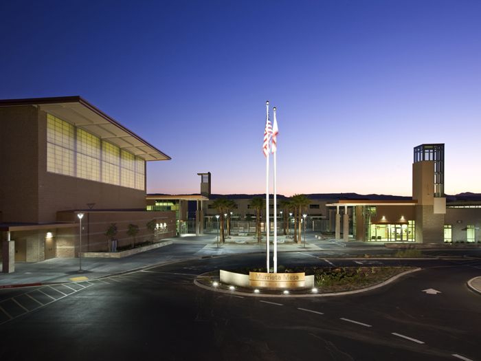 Building exterior at dusk with illuminated flagpoles and a central roundabout fountain