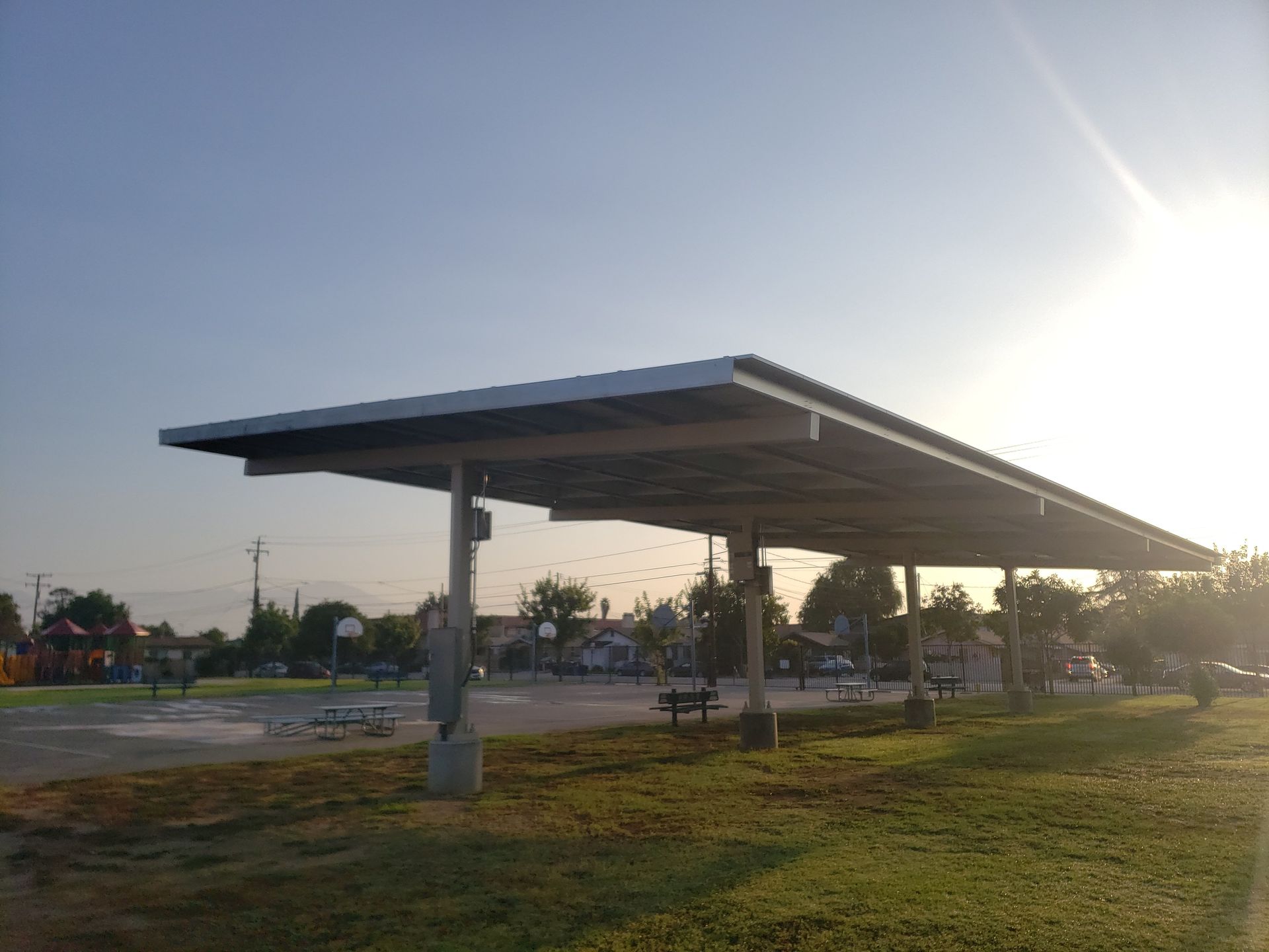 Solar panel canopy in a grassy parking lot at sunset