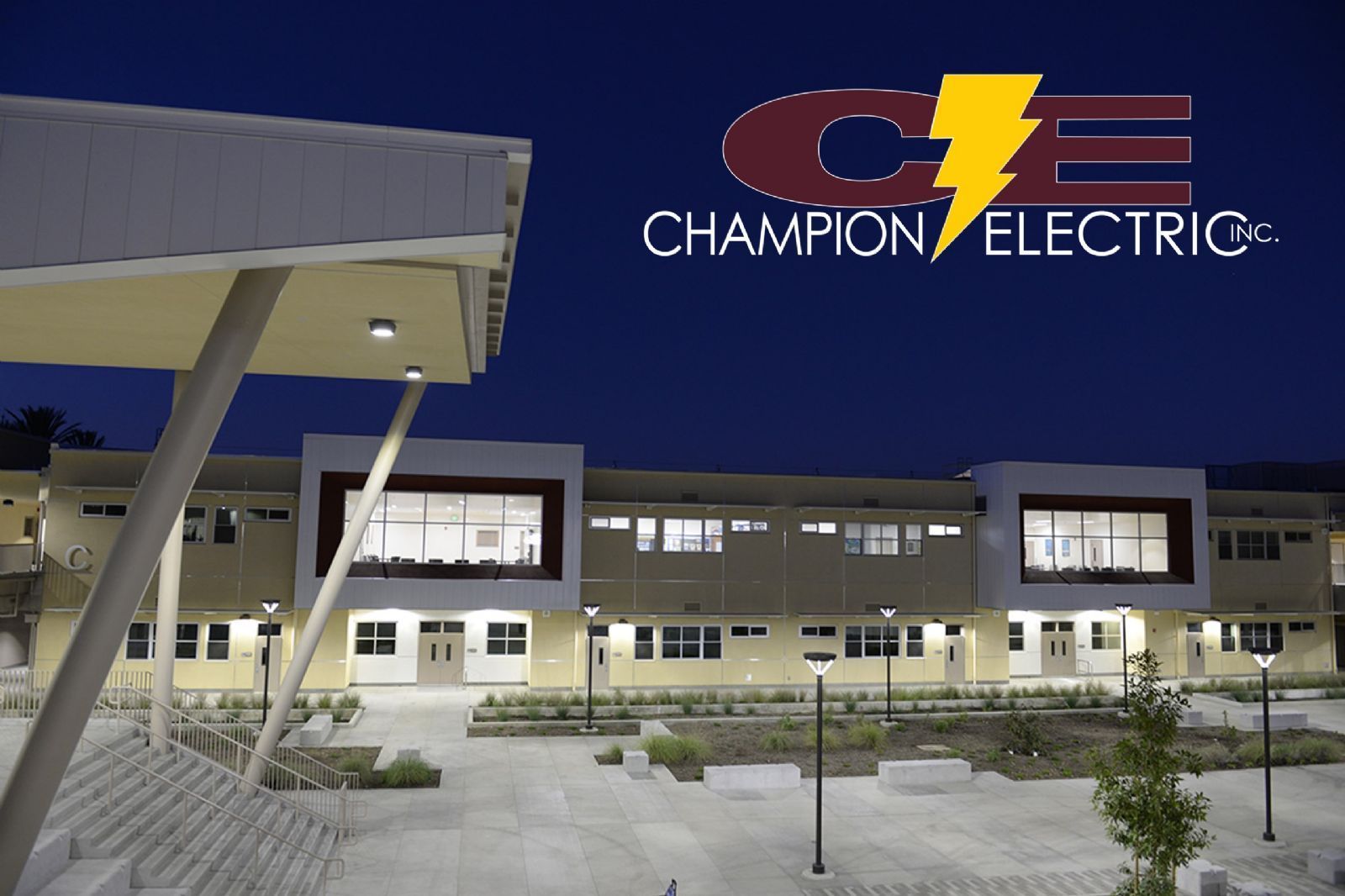 Champion Electric building exterior at night with illuminated logo and courtyard lights
