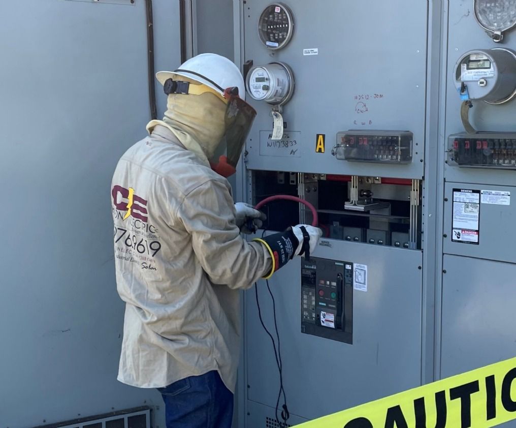 Utility worker in protective gear inspecting an electrical panel outdoors.