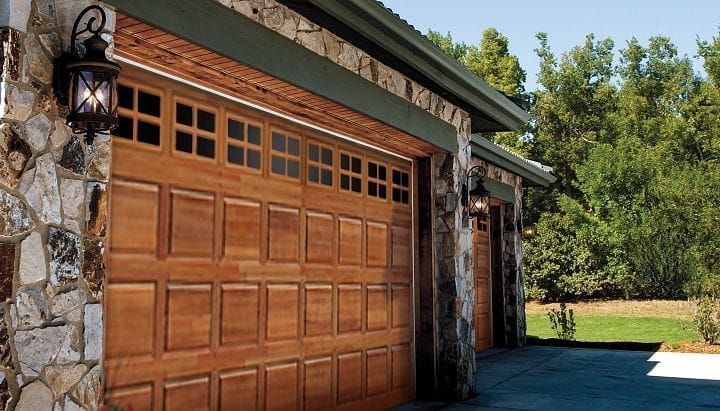 Wooden garage doors with stone accents and outdoor lights.