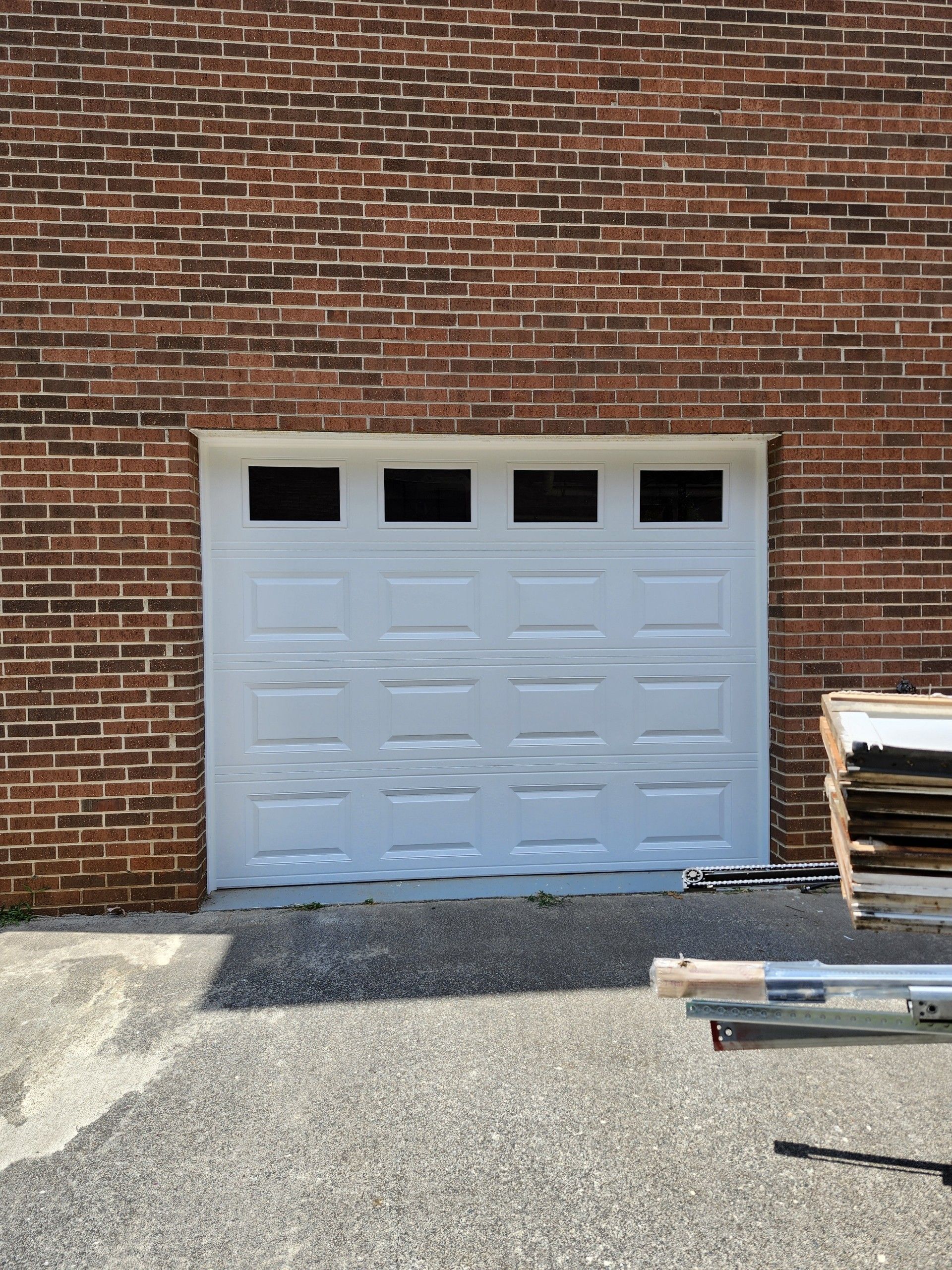 White garage door with four top windows in a brick building.