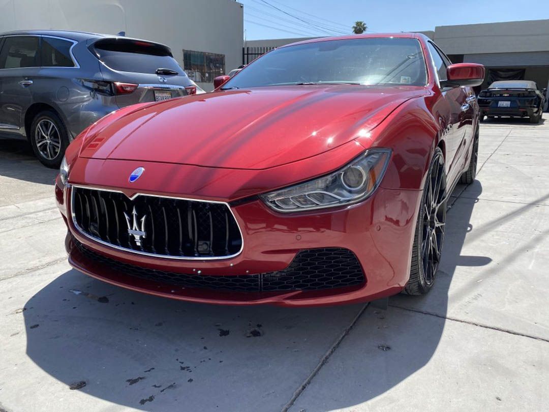 Red Maserati sedan parked outside on a sunny day.
