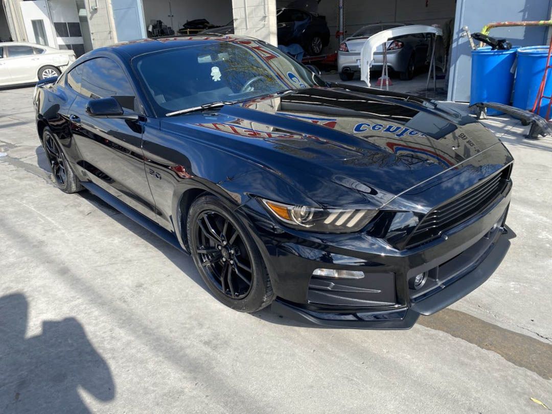Black Ford Mustang sports car parked outside a building.