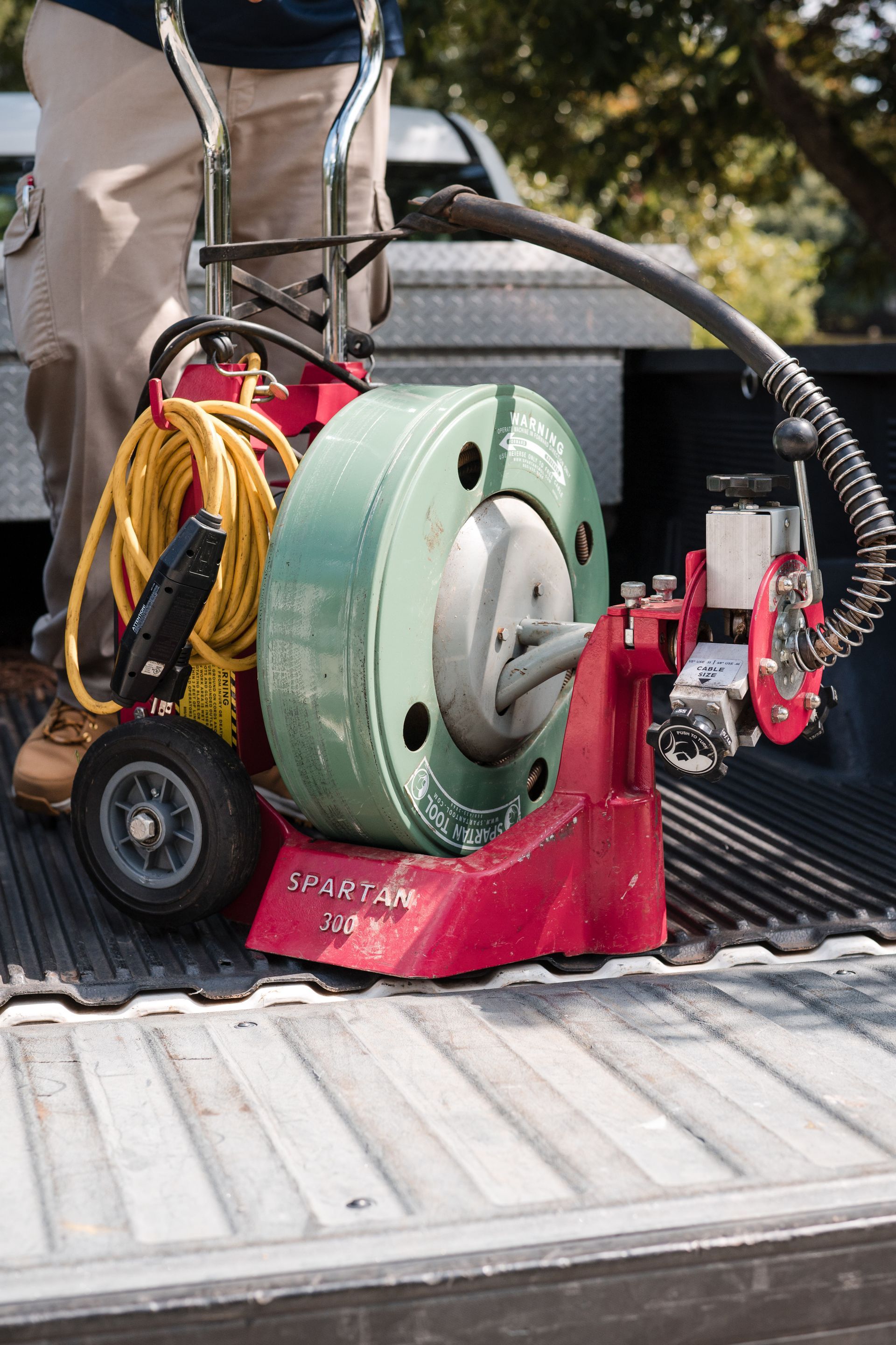Carpet cleaning machine and hoses in the back of a truck, with a worker standing nearby.