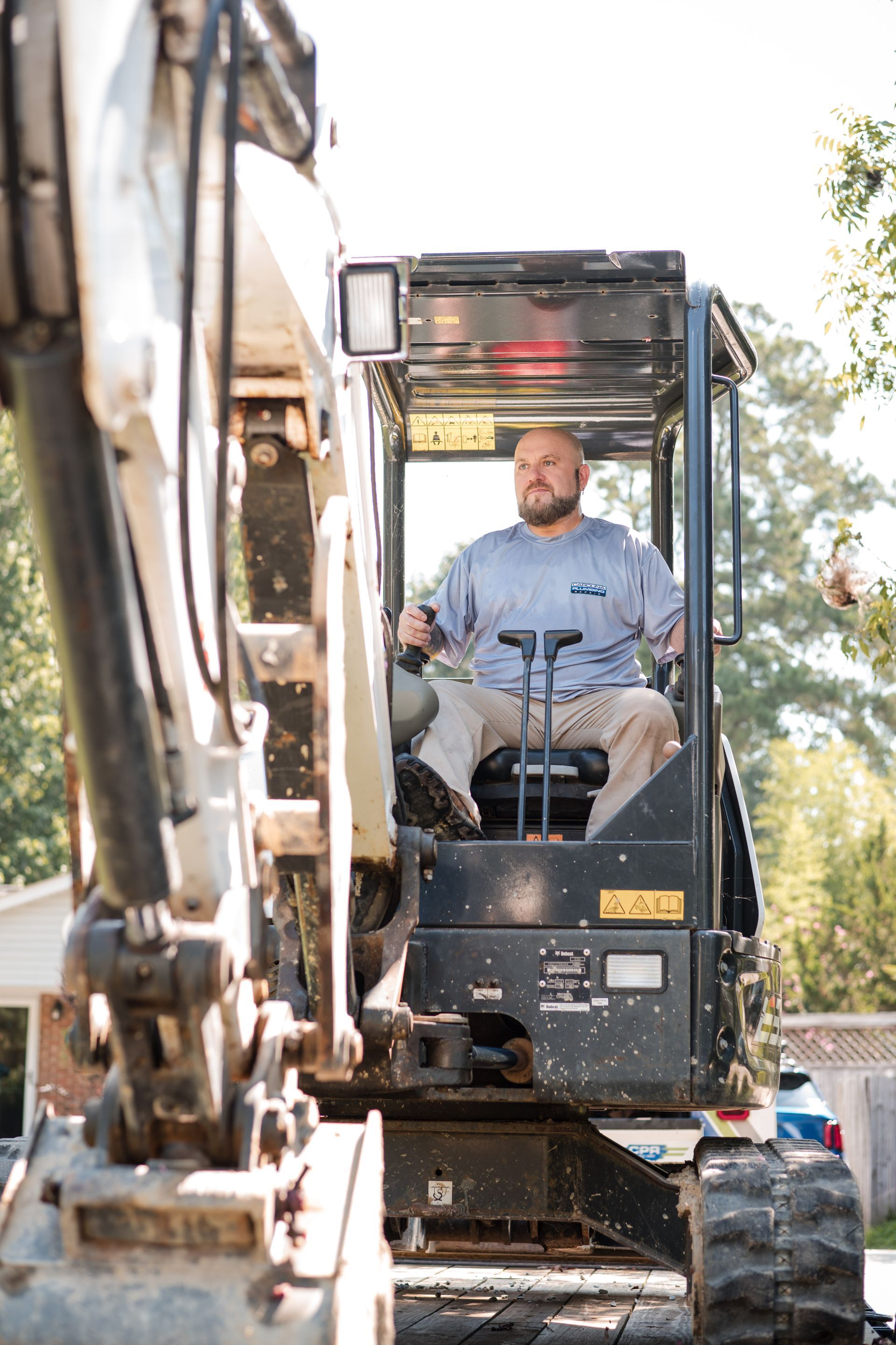 Operator seated in an excavator at a construction site, with the boom visible in the foreground.