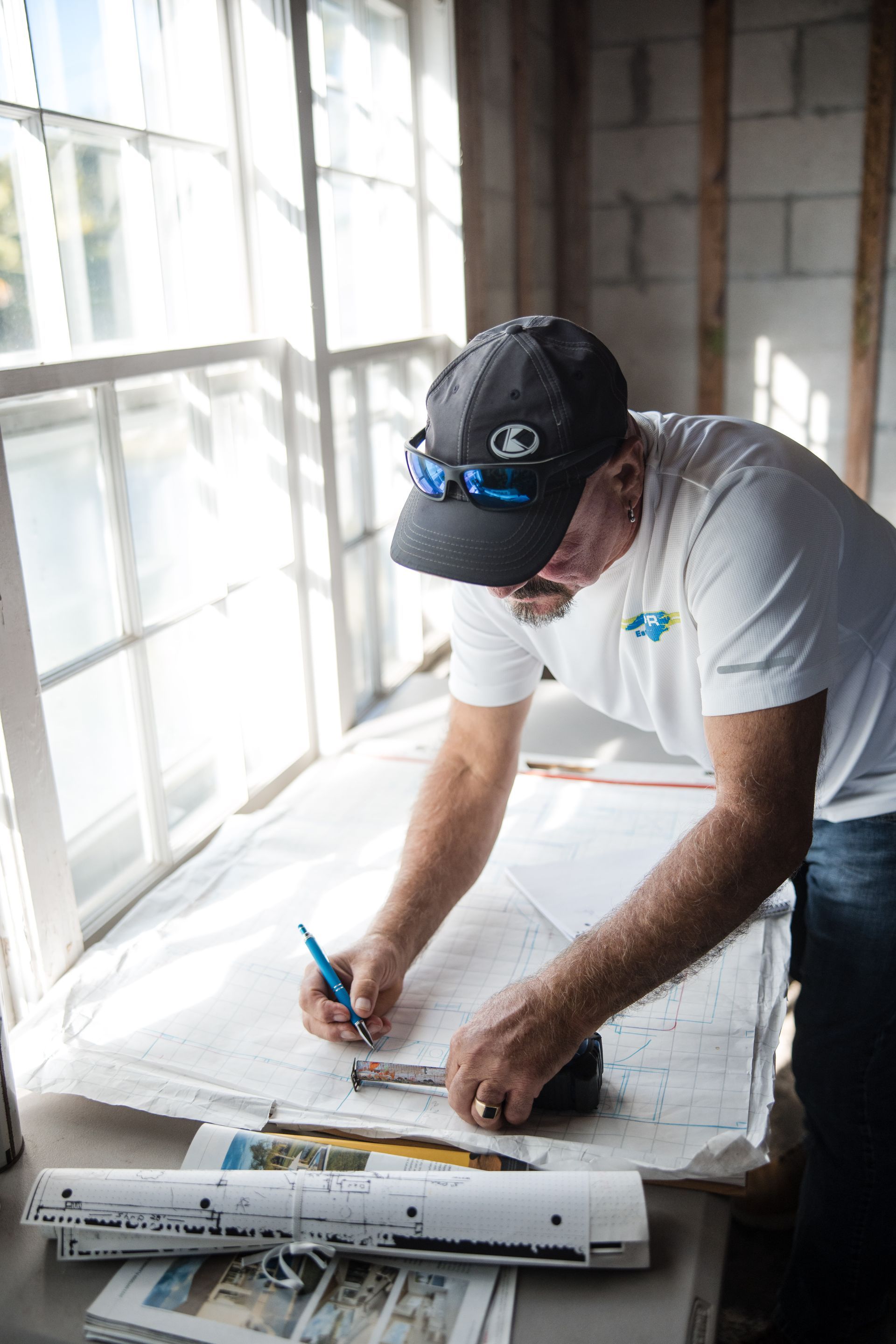 Person sketching on large paper plans by a bright window