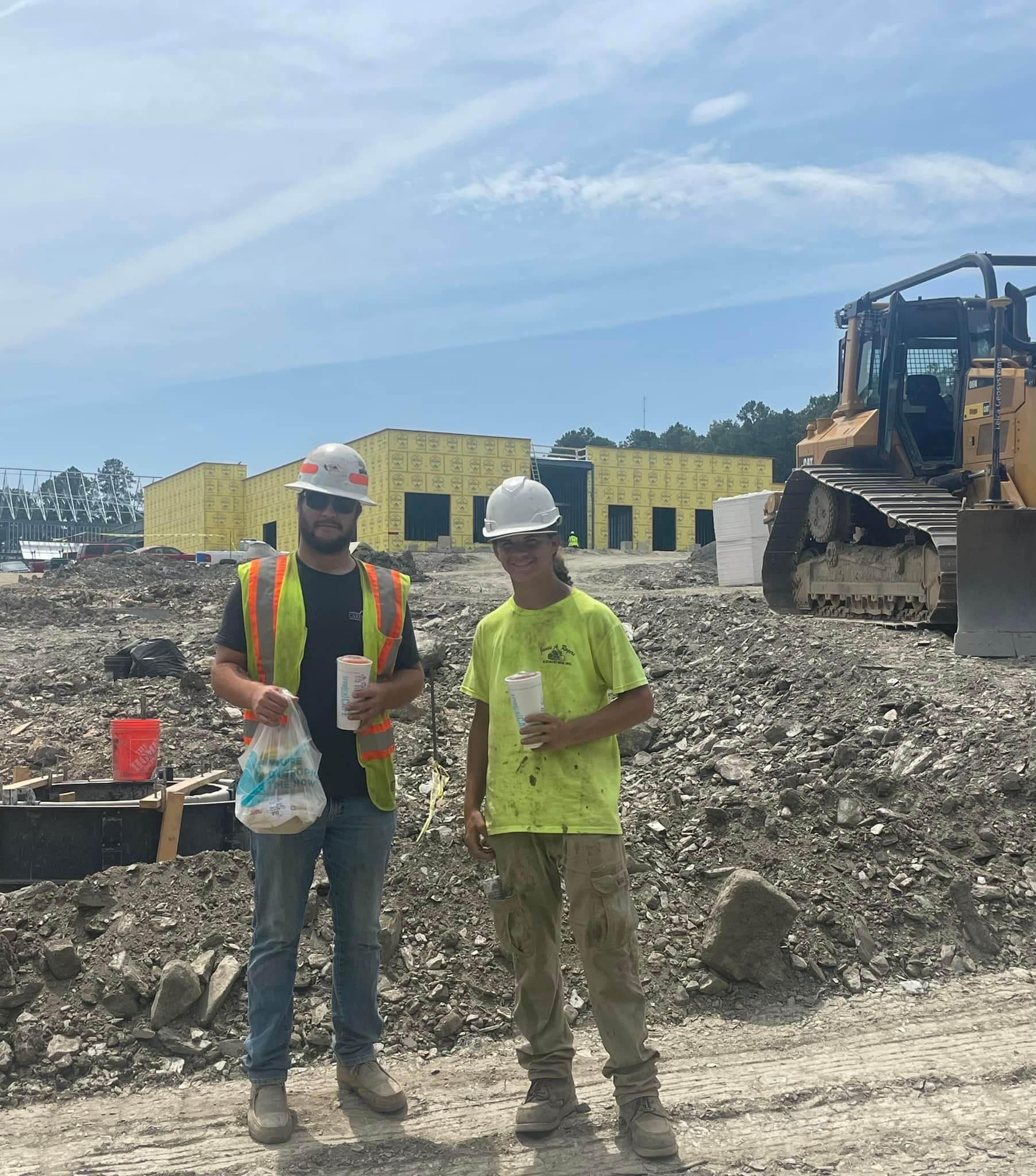 Two construction workers are standing in front of a building under construction.