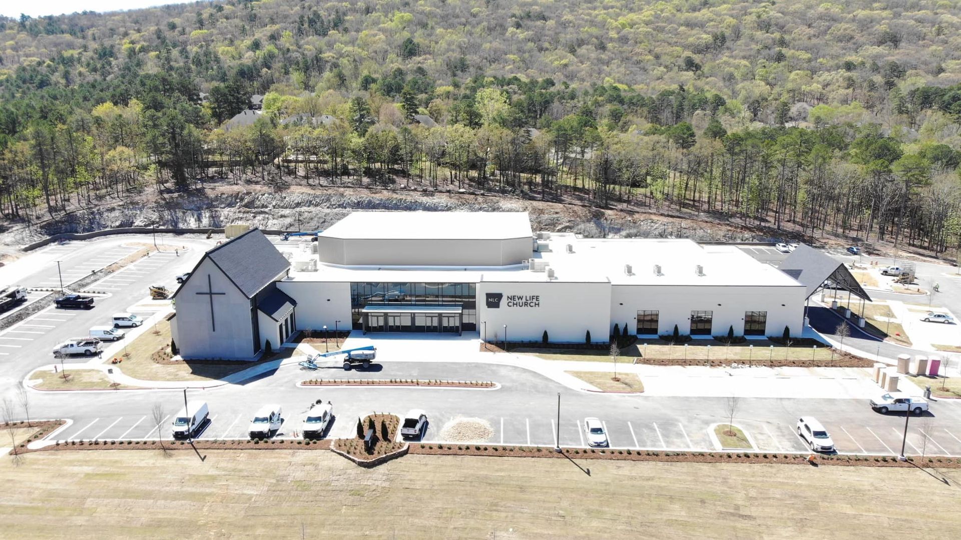 An aerial view of a church surrounded by trees and a parking lot