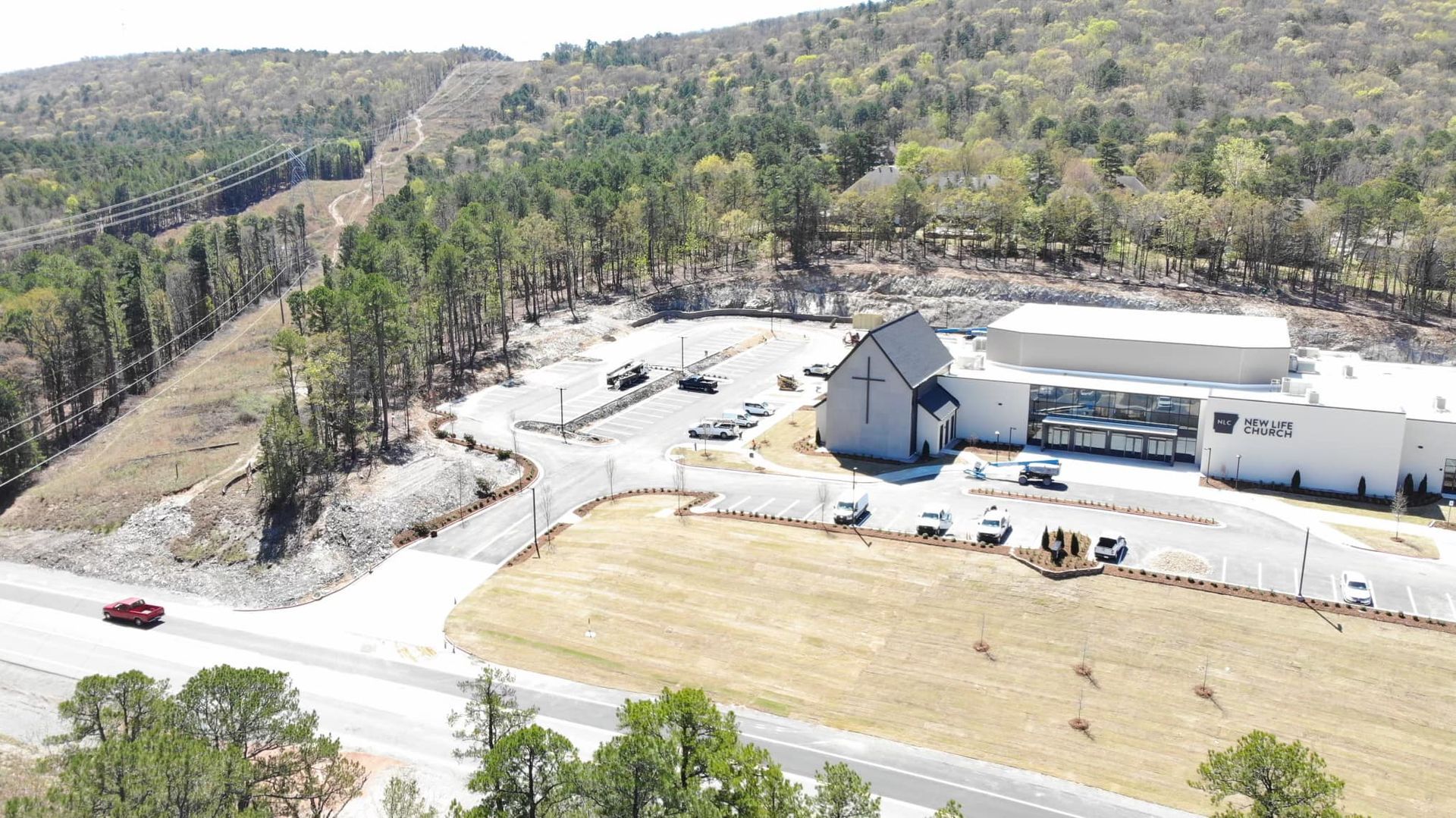 An aerial view of a church surrounded by trees and a road