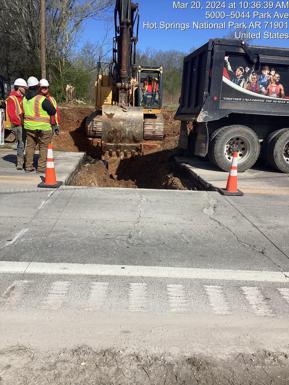 A group of construction workers are standing next to a dump truck.