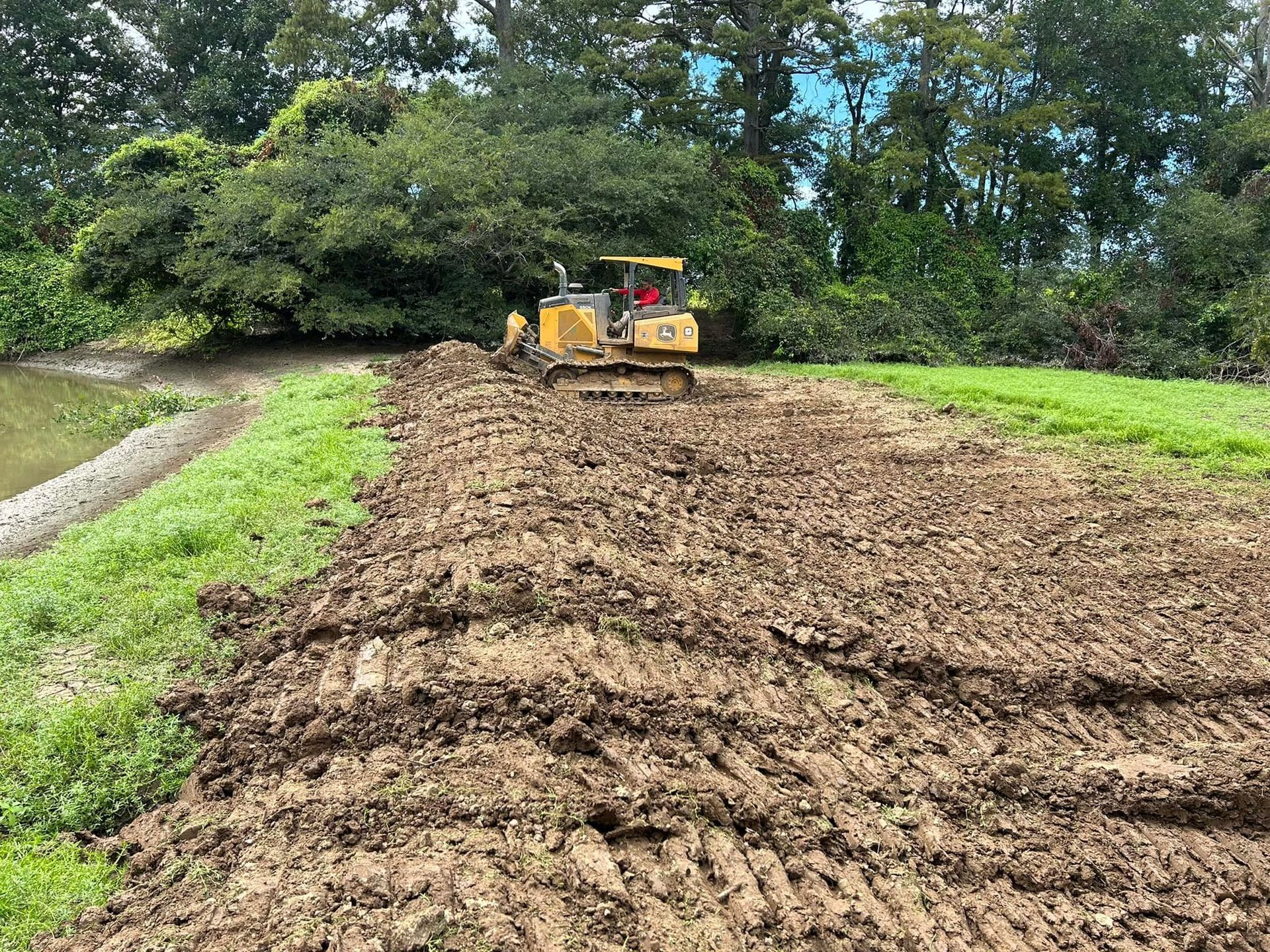 A bulldozer is plowing a dirt road in a field.