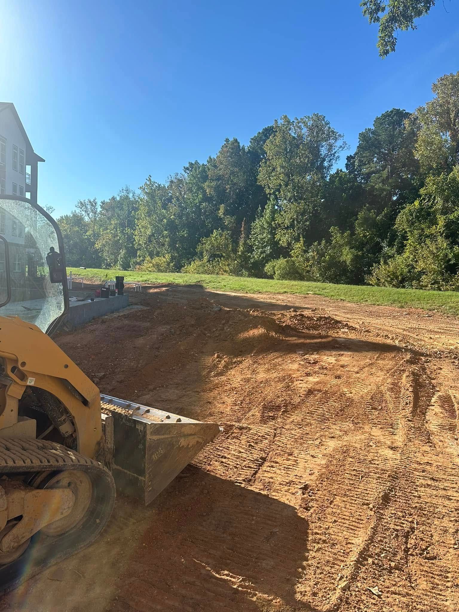 A bulldozer is moving dirt in a field with trees in the background.
