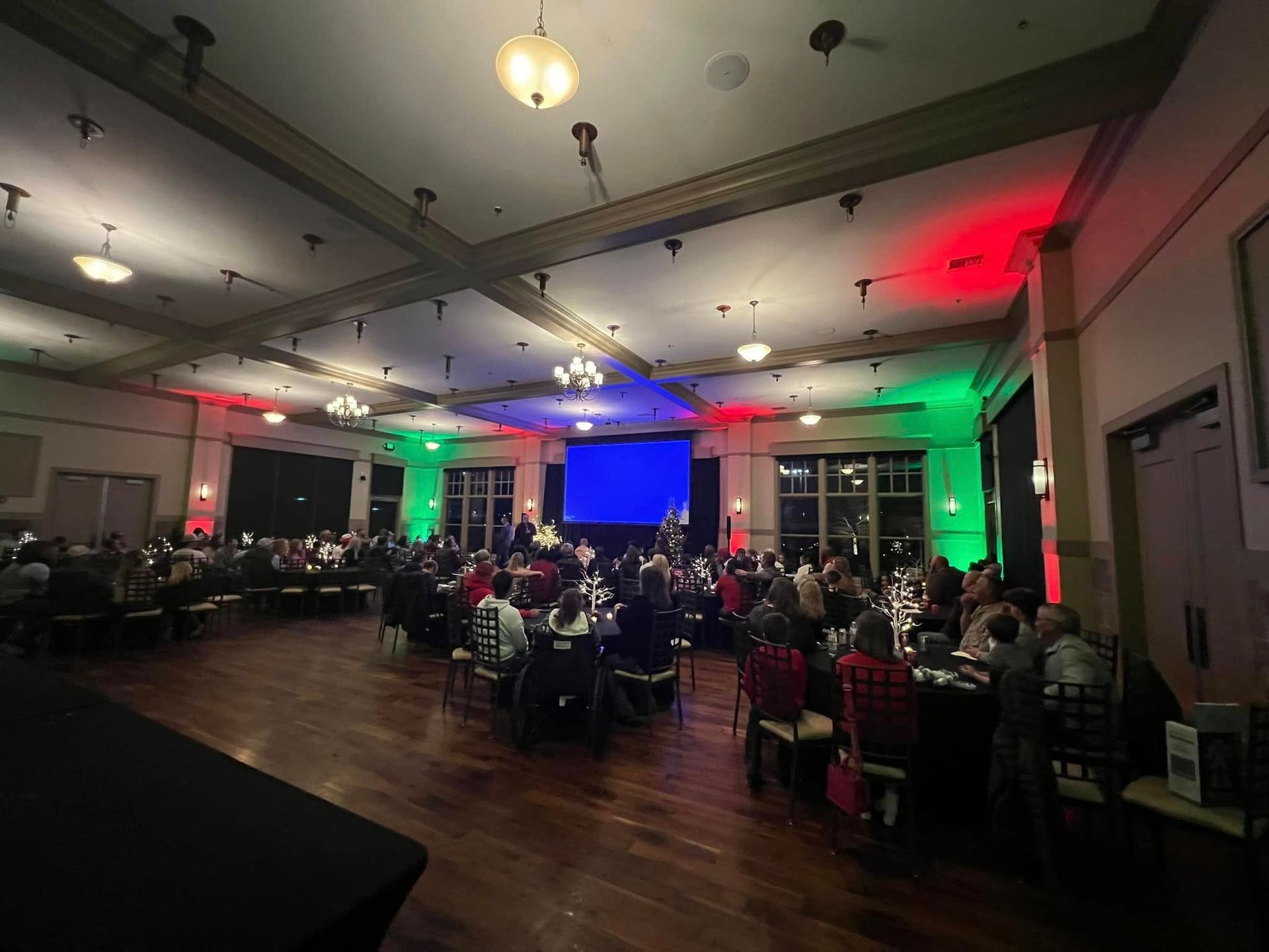 A large room with tables and chairs and a large screen.