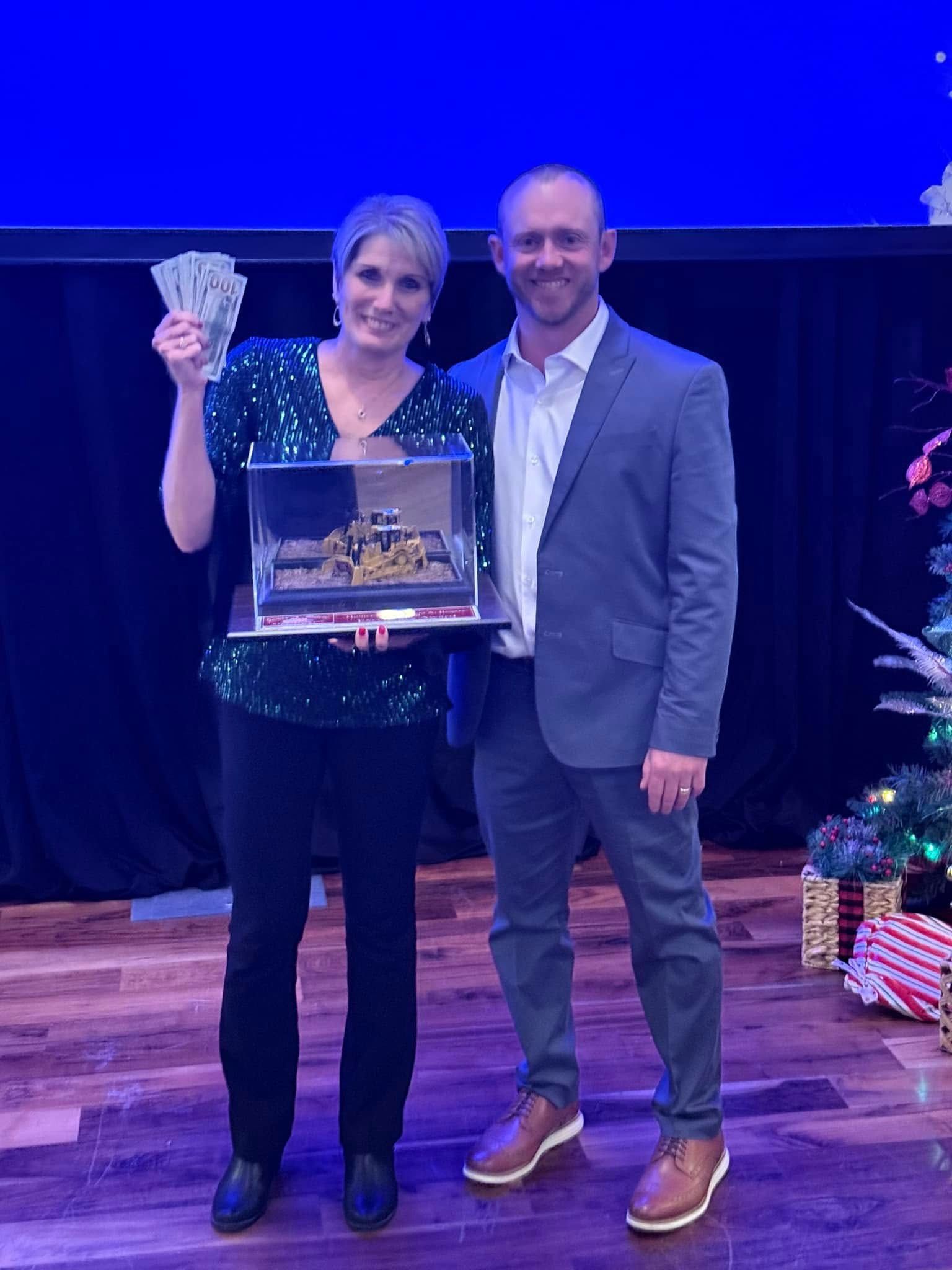 A man and a woman are standing next to each other holding a tray of money.