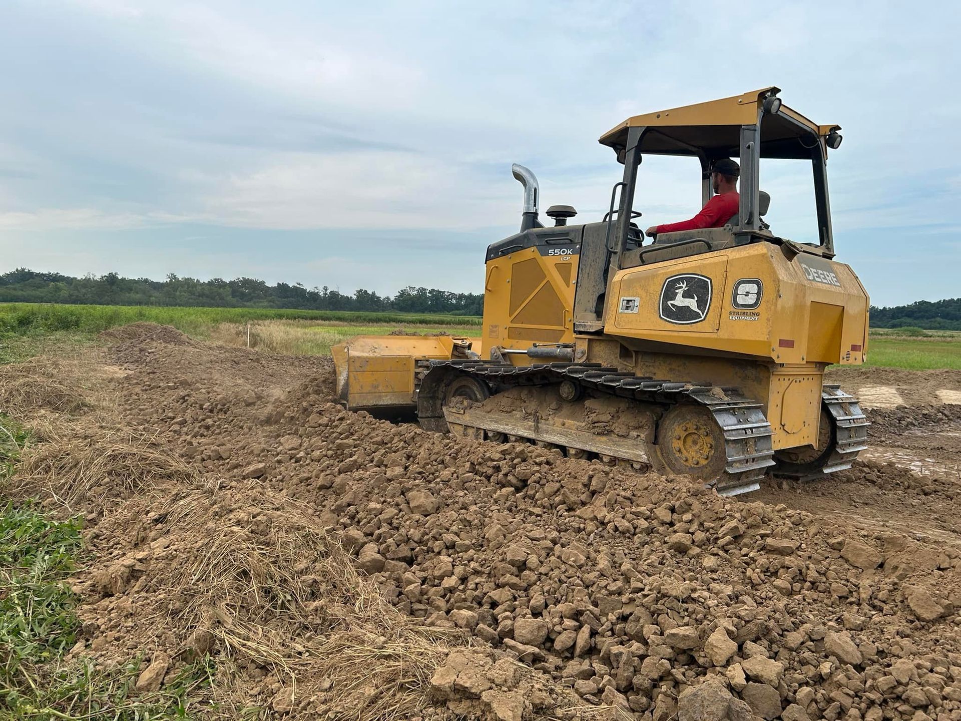 A man is driving a bulldozer through a dirt field.