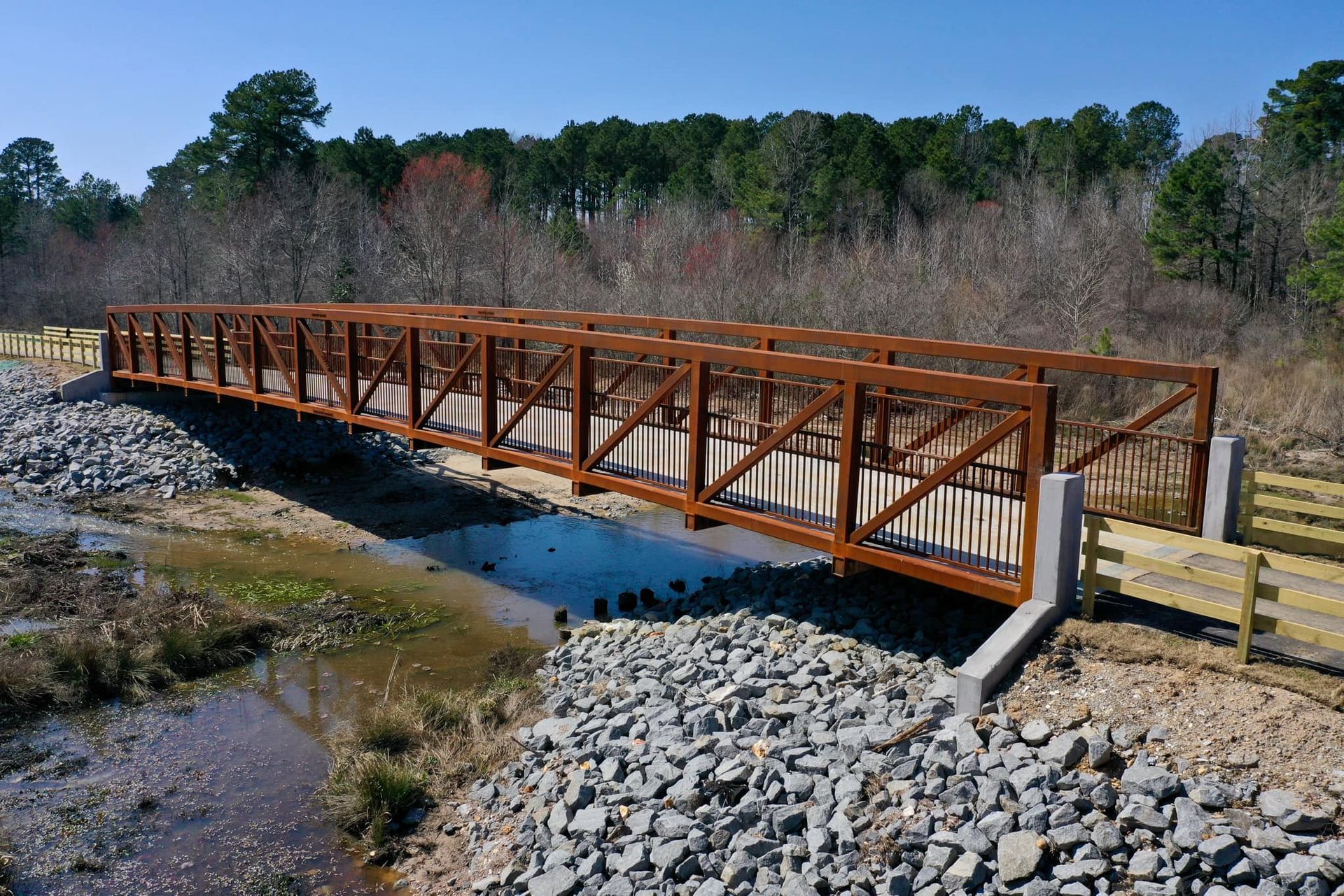 A wooden bridge over a stream with trees in the background