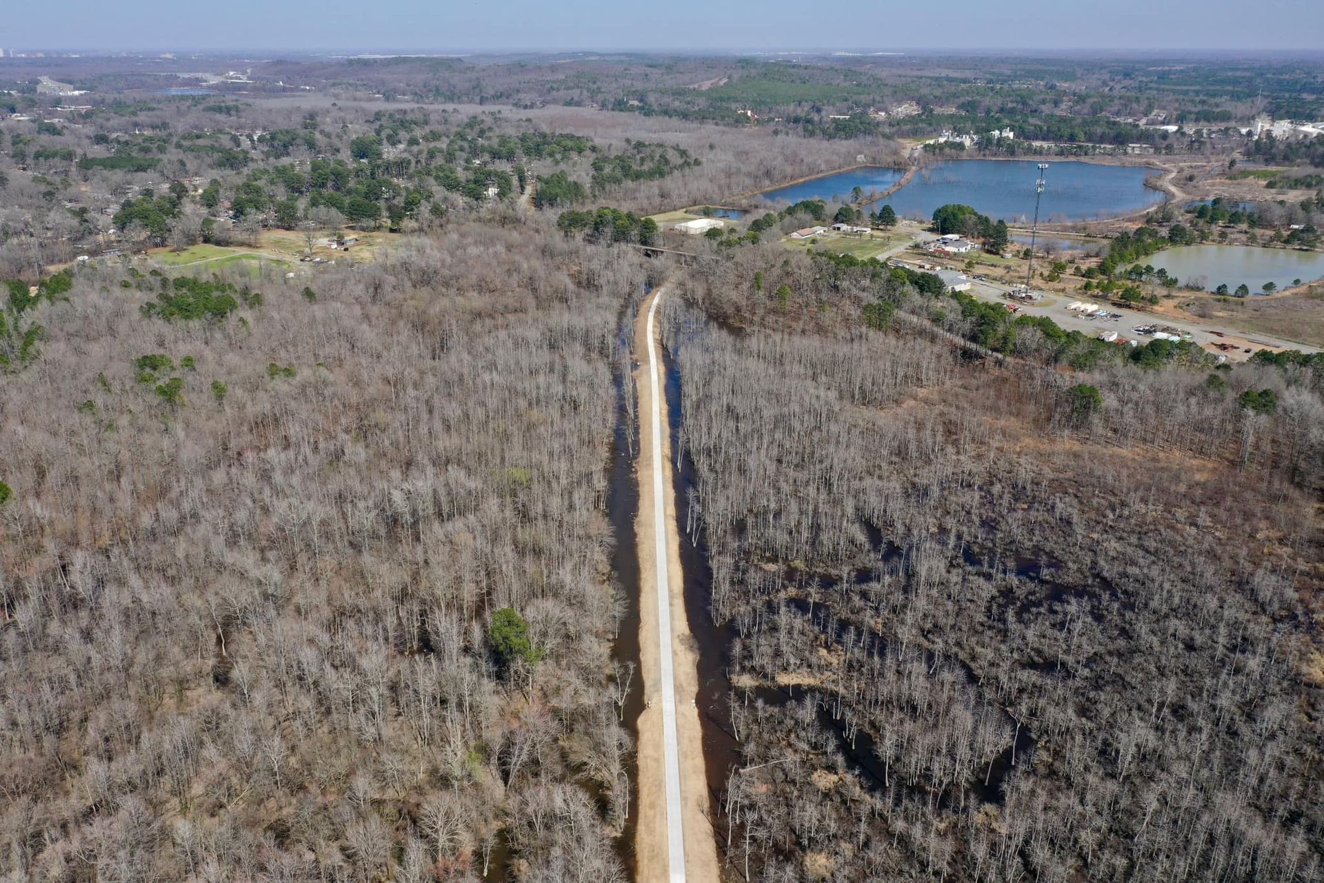 An aerial view of a dirt road going through a forest.