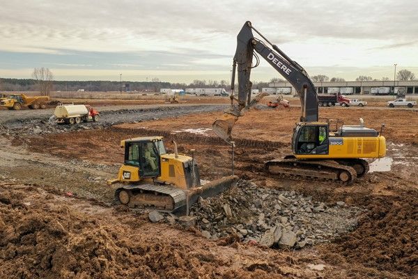 A bulldozer and an excavator are working on a construction site.