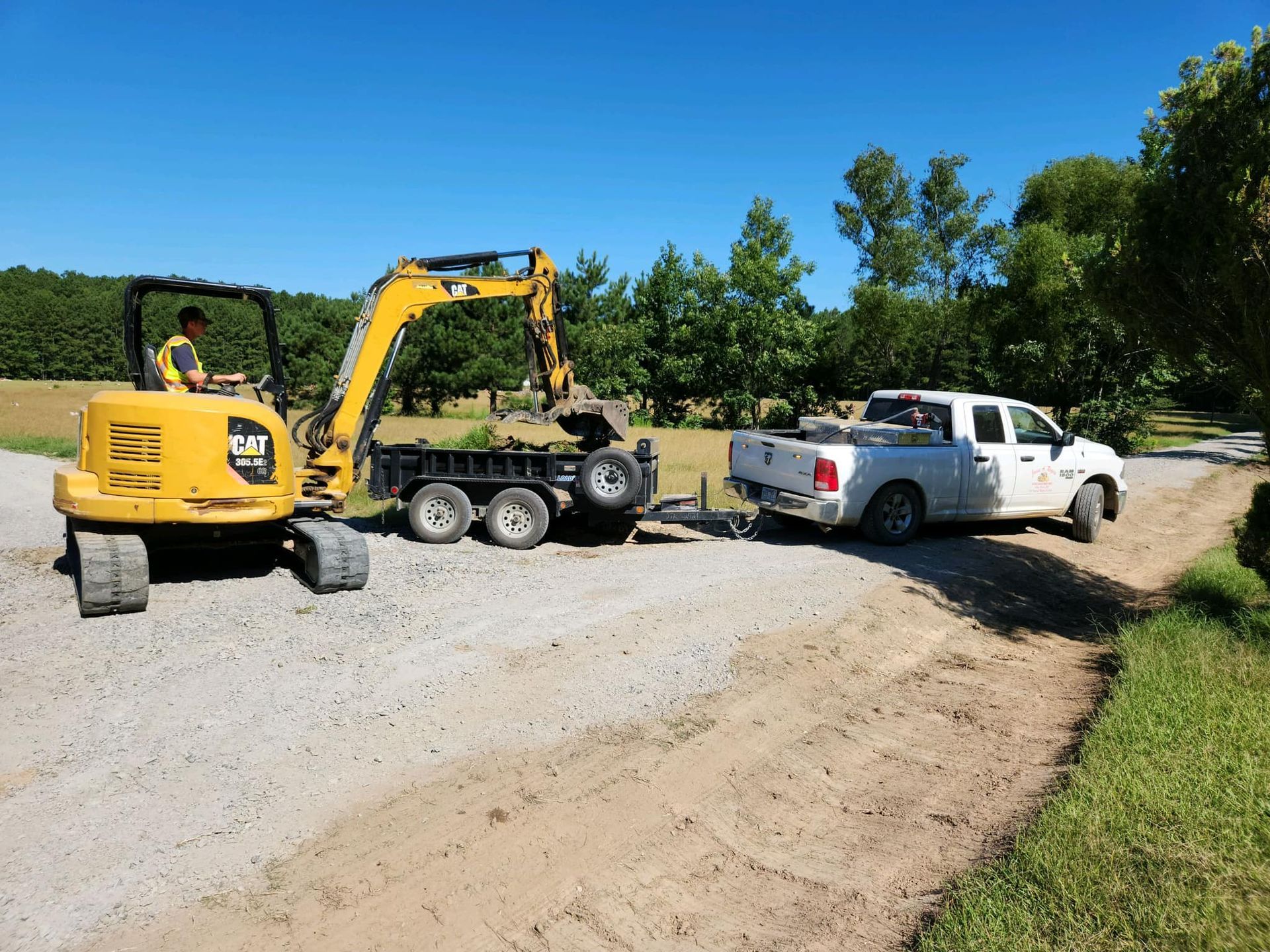A yellow excavator is being towed by a white truck