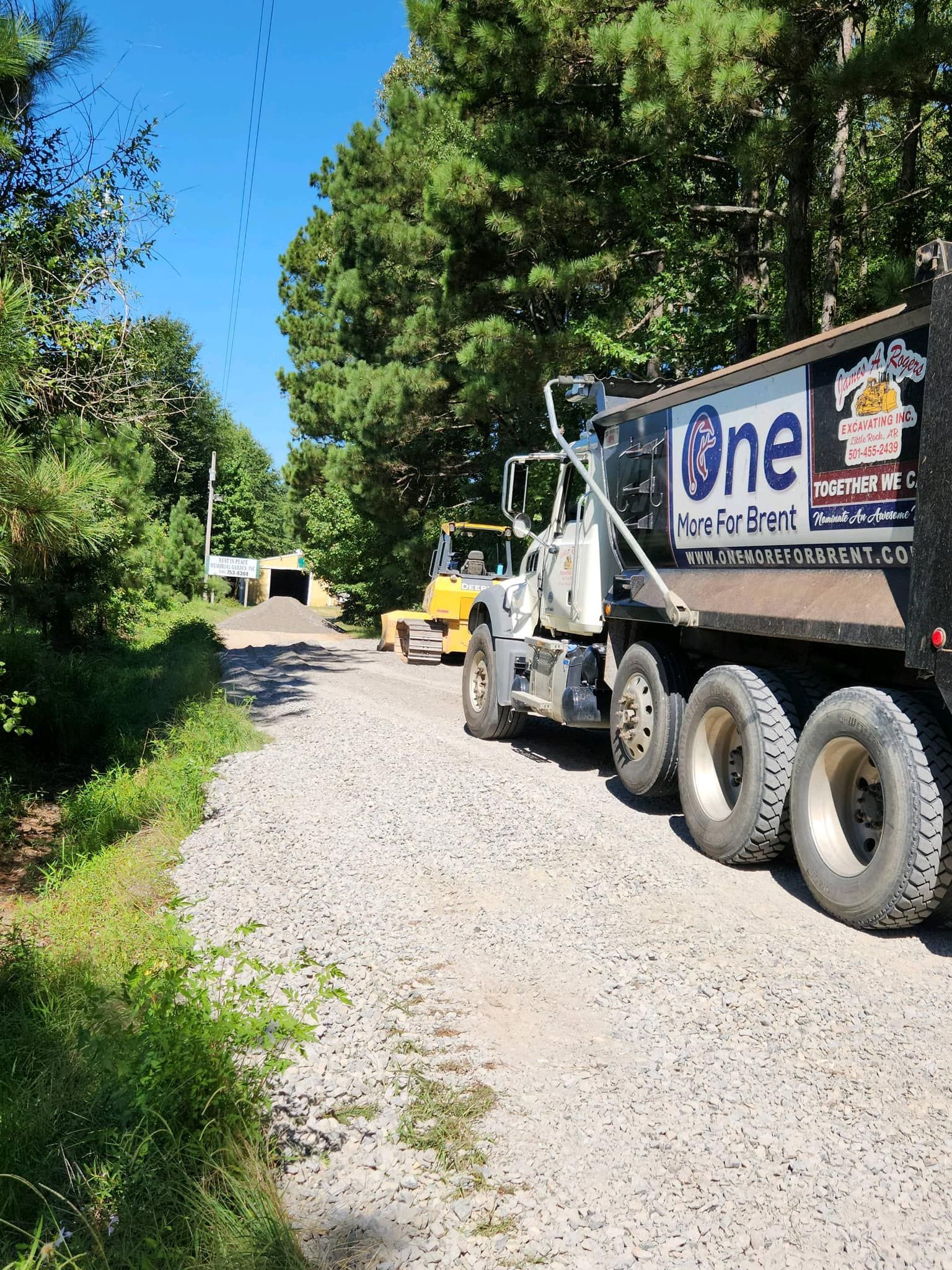 A dump truck is parked on the side of a gravel road.