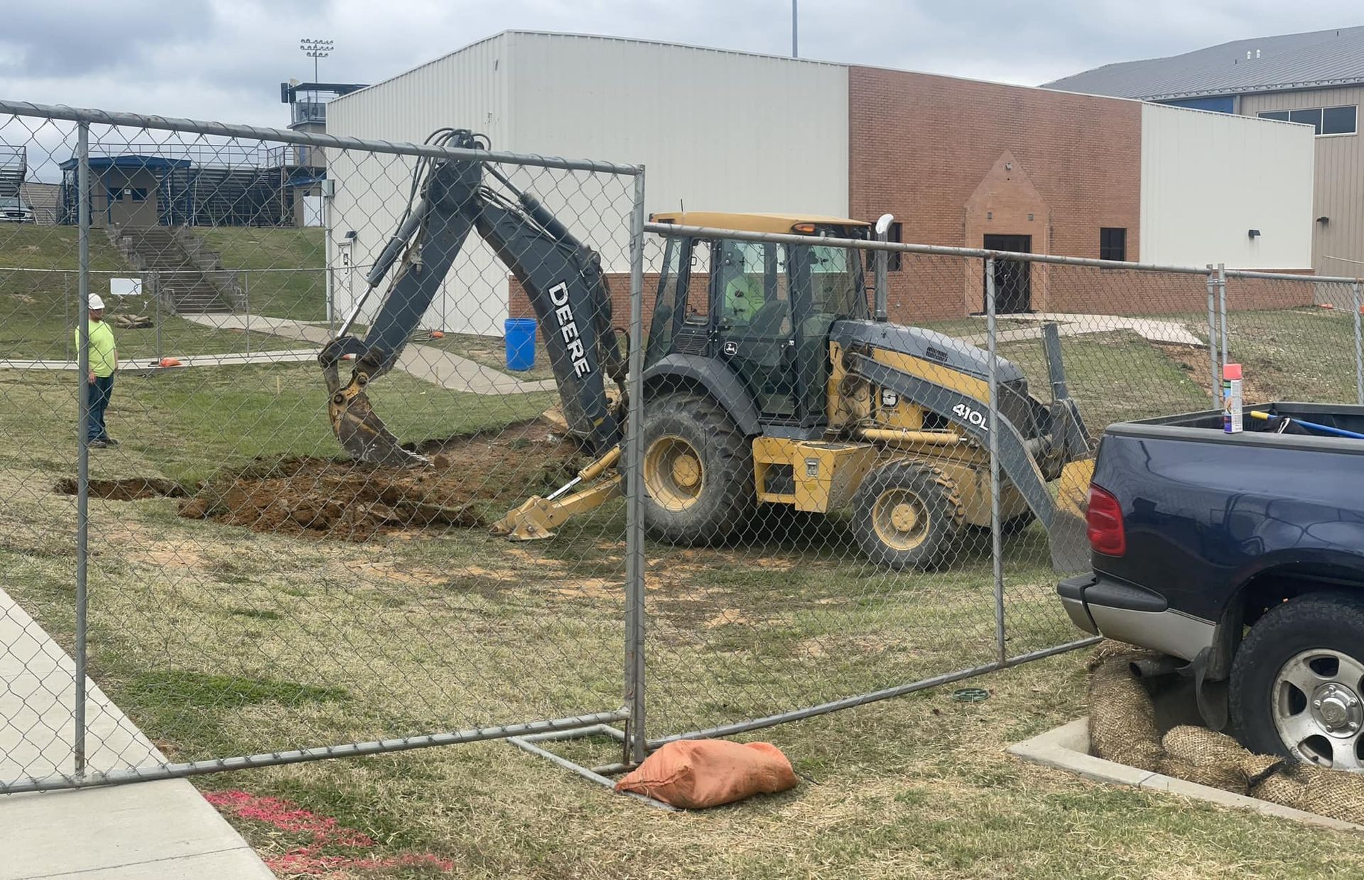 A tractor is digging a hole in the ground in front of a building.
