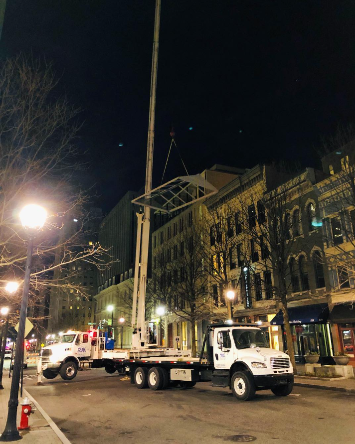 A white truck with a crane on the back is parked on a city street at night