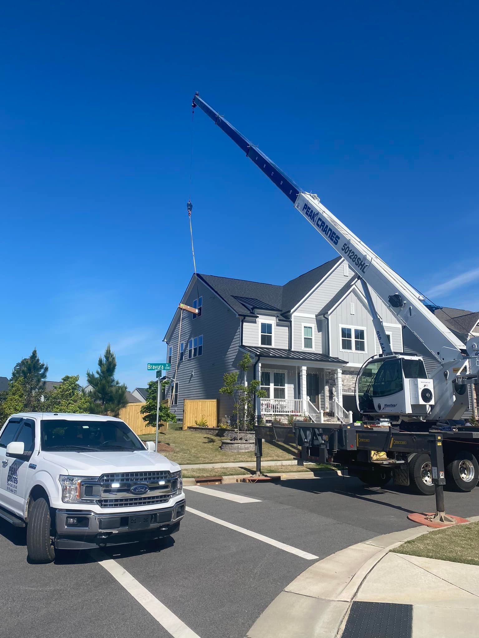 A white truck is driving down a street in front of a house.