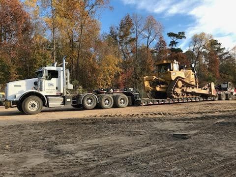 A semi truck is carrying a bulldozer on a trailer.