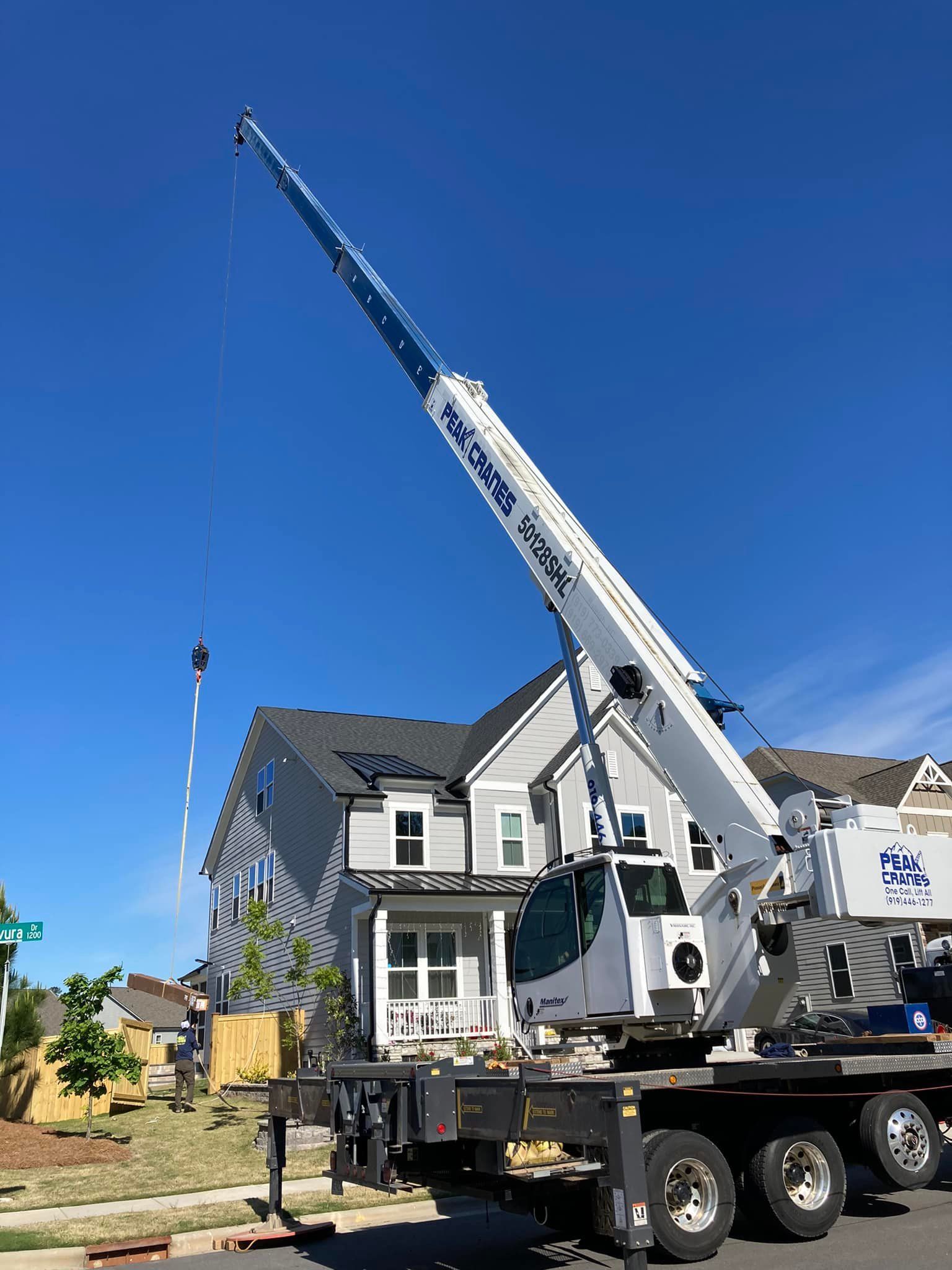 A large crane is sitting on top of a truck in front of a house.