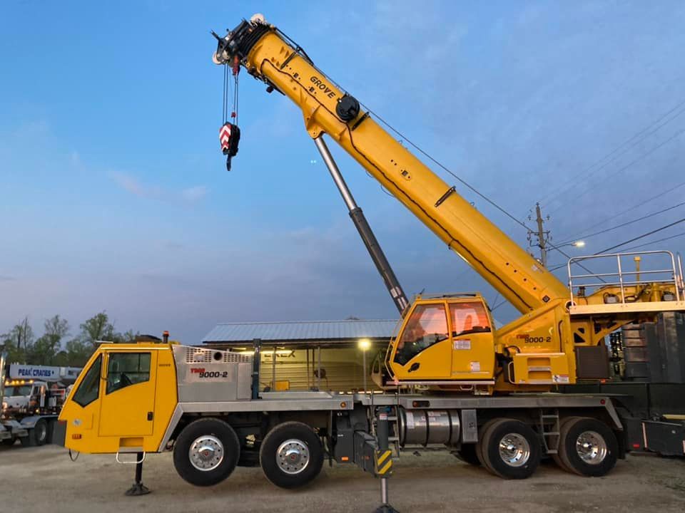 A large yellow crane is parked in front of a building