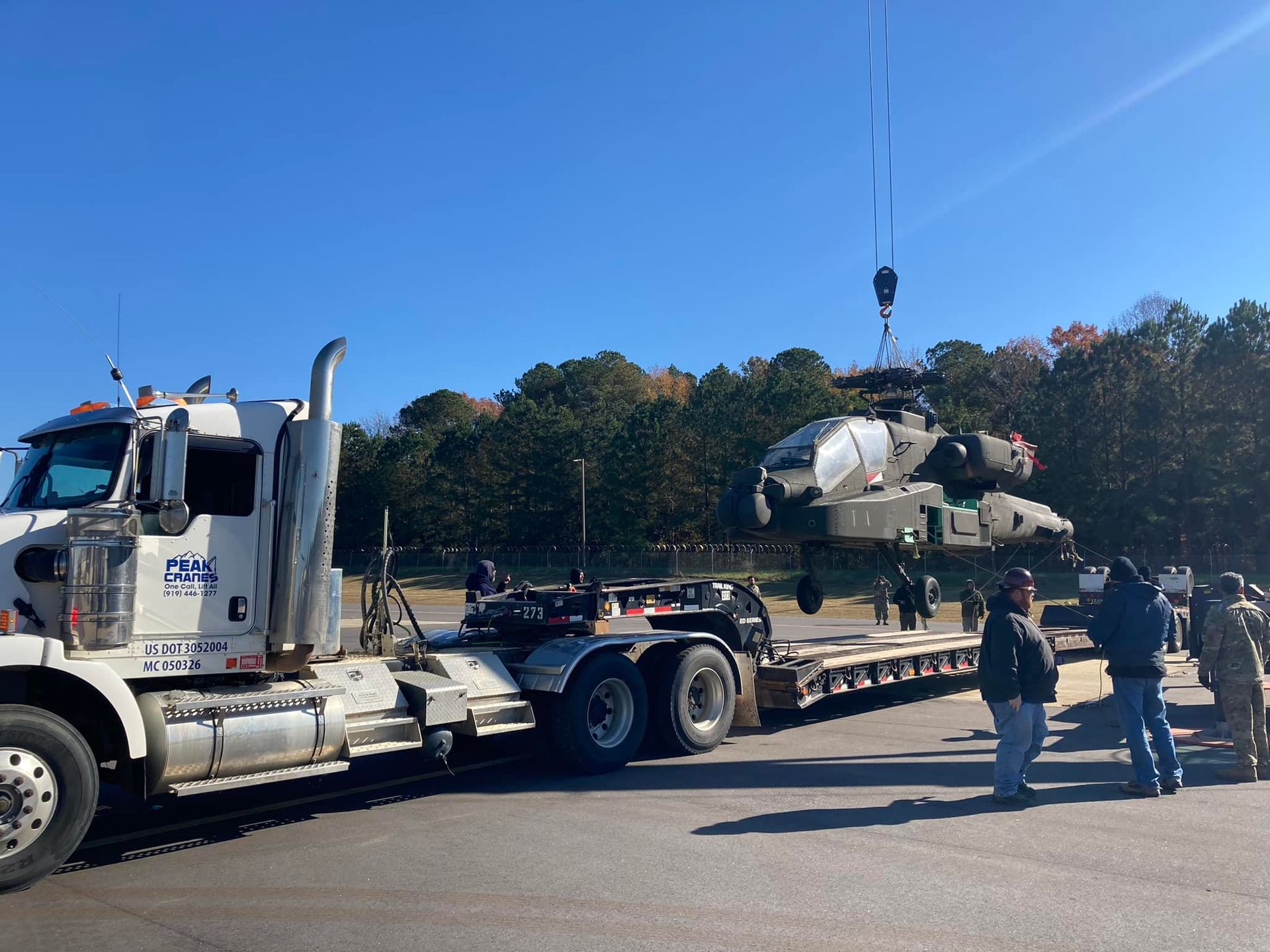 A semi truck is carrying a helicopter on a trailer